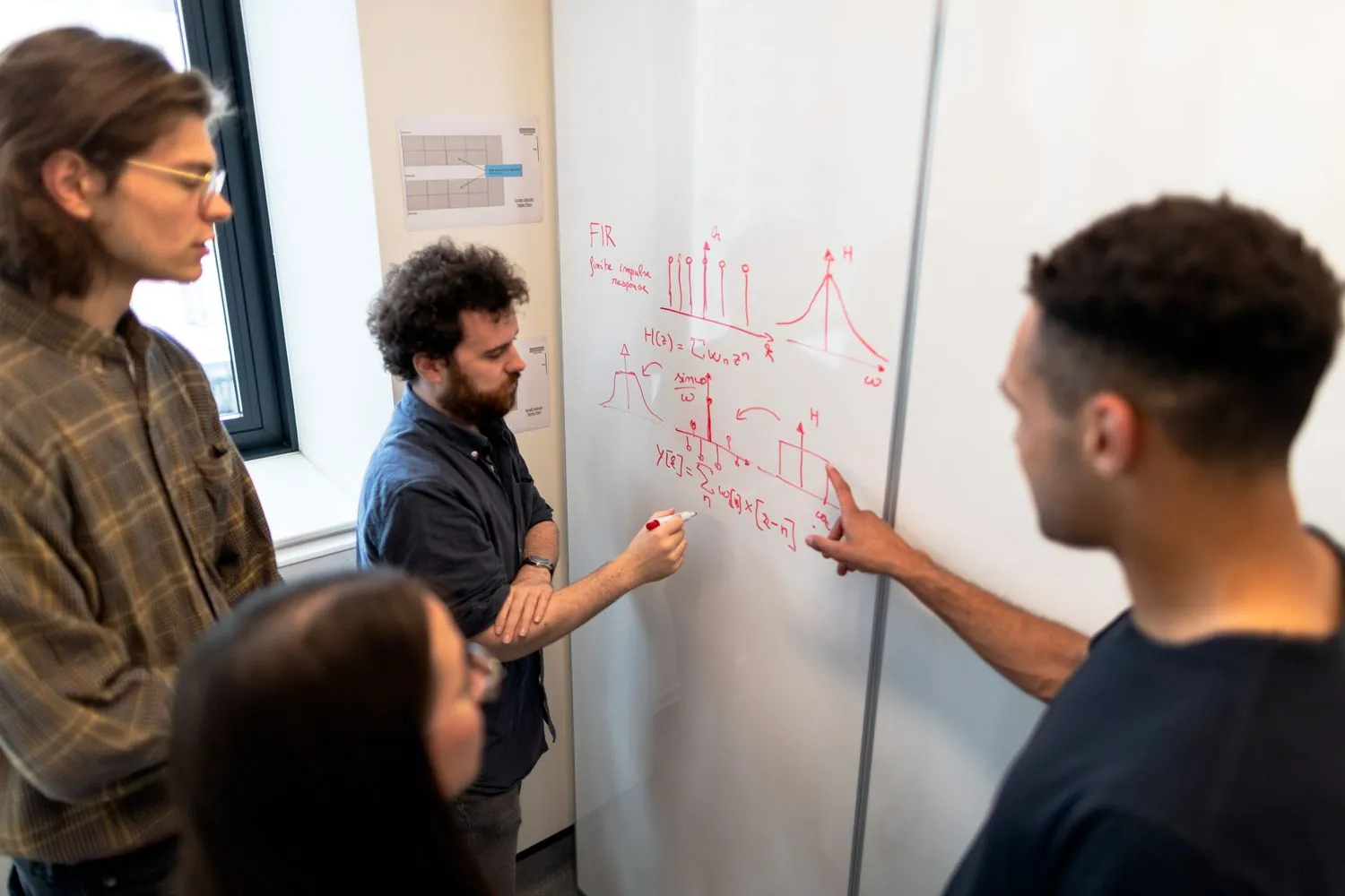 Equipo técnico contrastando fórmulas, gráficas y modelos matemáticos en una pizarra