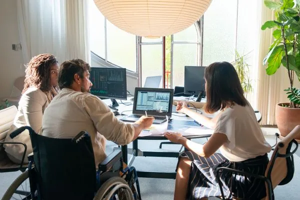 Equipo analizando gráficas en una laptop y monitores de oficina